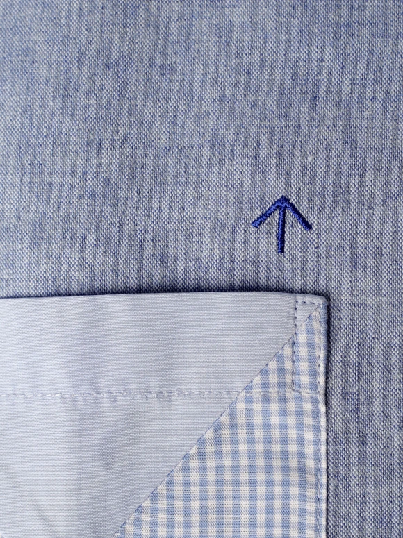 Close-up of a blue textile pocket and embroidered arrow